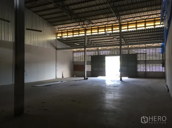 Warehouse for rent in Min Buri, Bangkok - Open-plan warehouse hall with large sliding steel doors, clerestory lights and concrete flooring.