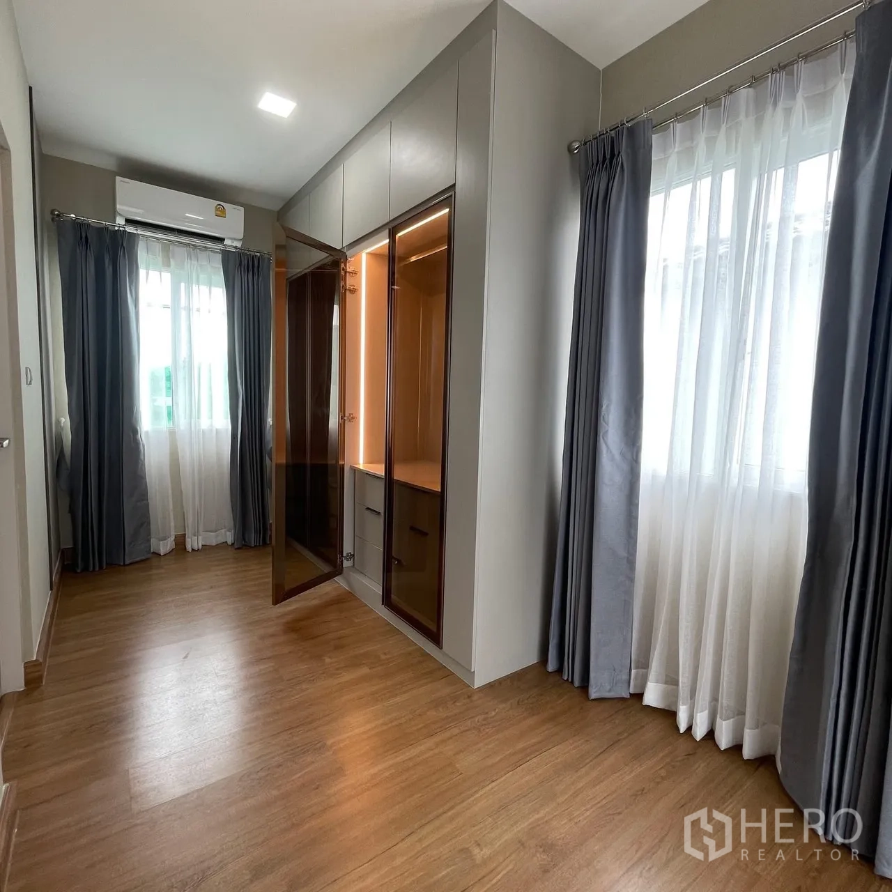 Semi-detached House for rent in Bang Phli, Samut Prakan - Bright bedroom corner with large windows, wood floors, and an illuminated built-in wardrobe.