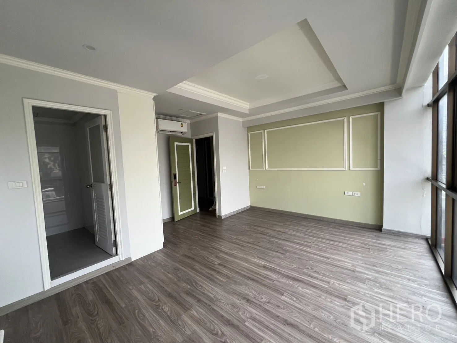 店屋 出租在Bang Rak, Bangkok - 采光充足的楼上房间，木地板、绿色点缀墙与大窗户。