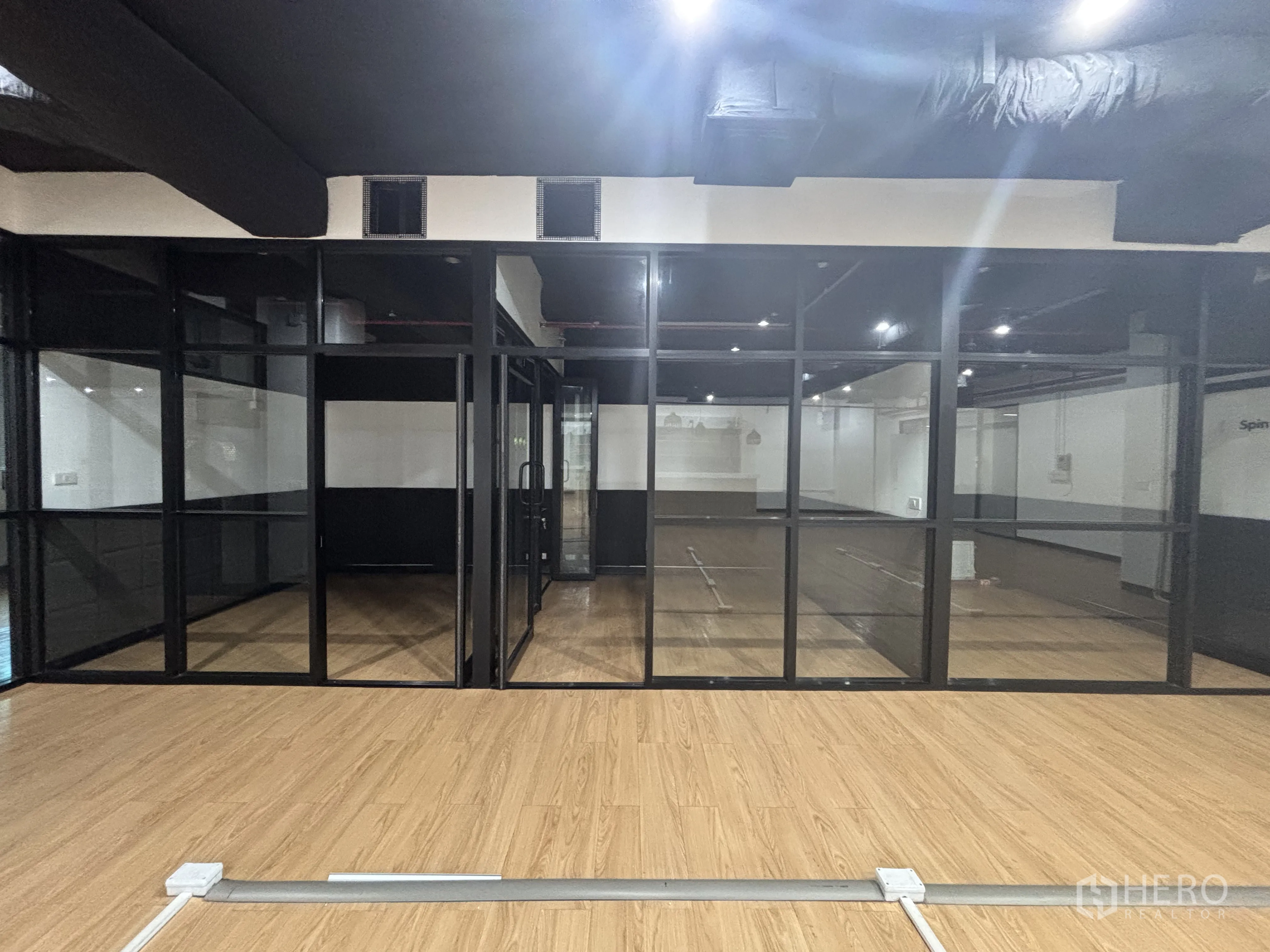 Office Space for rent in Bang Rak, Bangkok - Glass-partitioned meeting rooms facing an open workspace with timber floors.