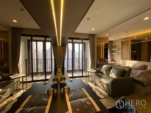 คอนโด ให้เช่าในWatthana, Bangkok - แปลนเปิดโล่ง โต๊ะทานข้าวและโซฟาหันสู่ระเบียงกว้าง ไฟซ่อนโทนอุ่น พร้อมวิวสกายไลน์