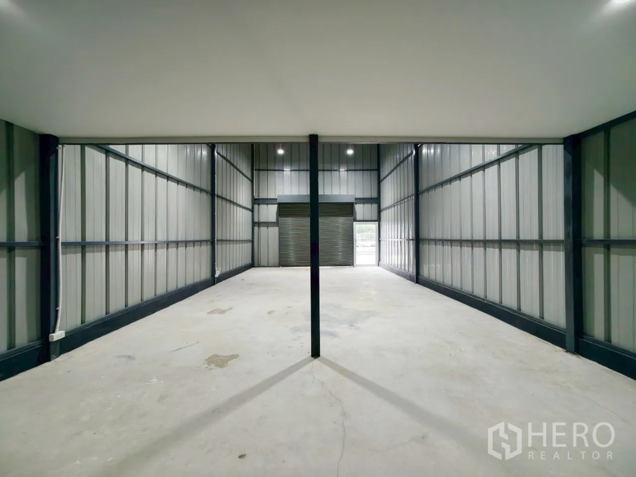 Warehouse for rent in Phra Khanong, Bangkok - View from beneath the mezzanine toward the roller shutter entry with drive-in access.