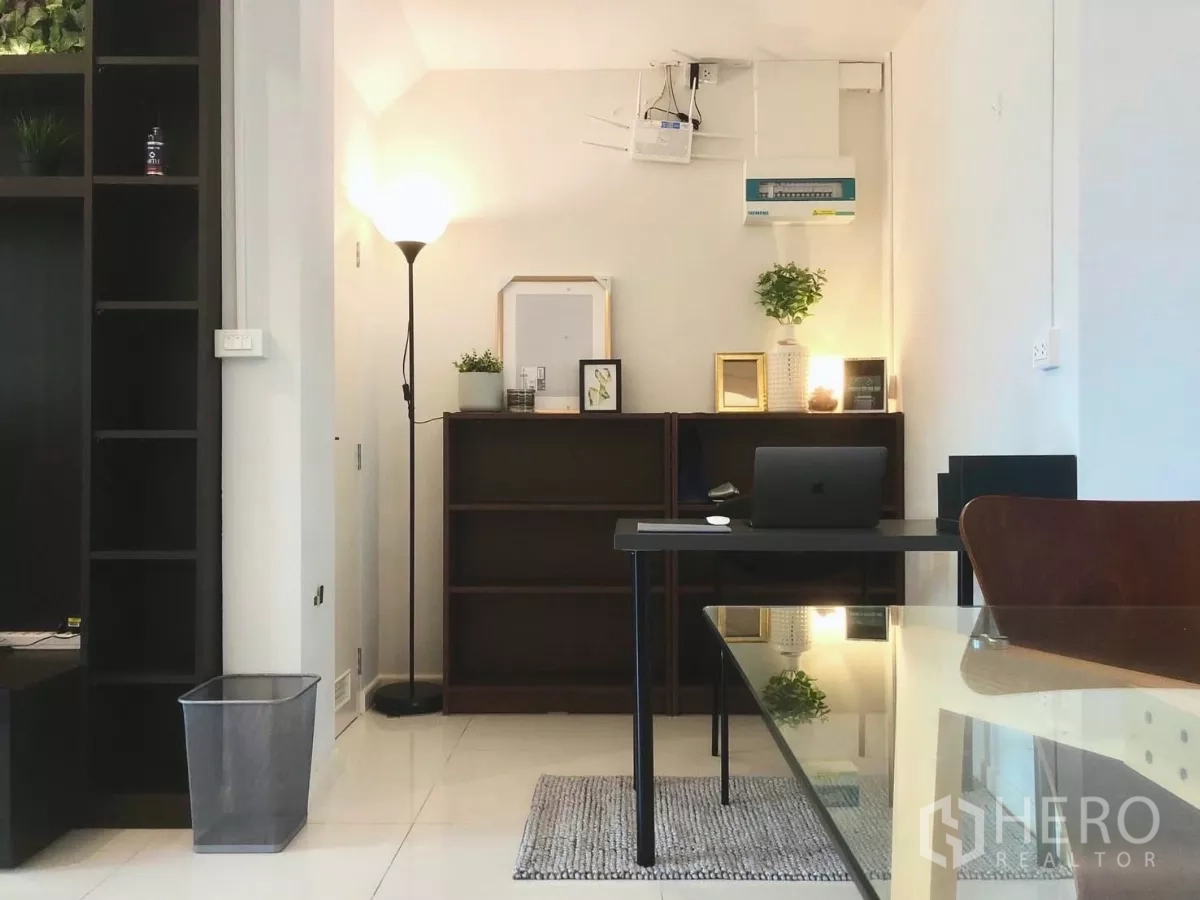 Townhouse for rent or sale in Bang Phli, Samut Prakan - Cozy study corner with desk, floor lamp and shelving in a minimalist interior.