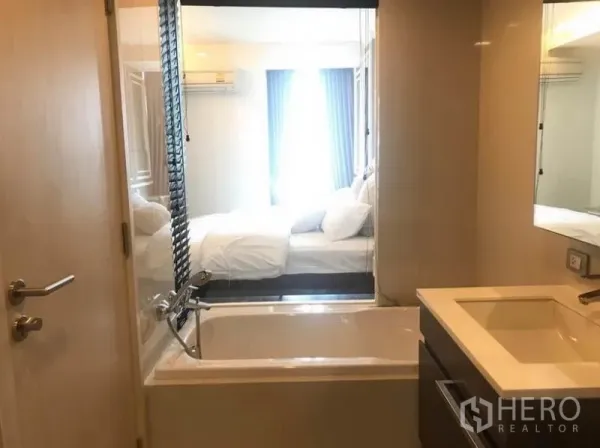 公寓 出租在Watthana, Bangkok - 浴室带浴缸与台盆，玻璃隔断连接卧室，引入自然采光。