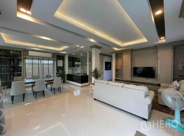 Detached House for rent or sale in Bang Phli, Samut Prakan - Open-plan living and dining space with recessed lighting, glossy floors and TV wall beside the kitchen.