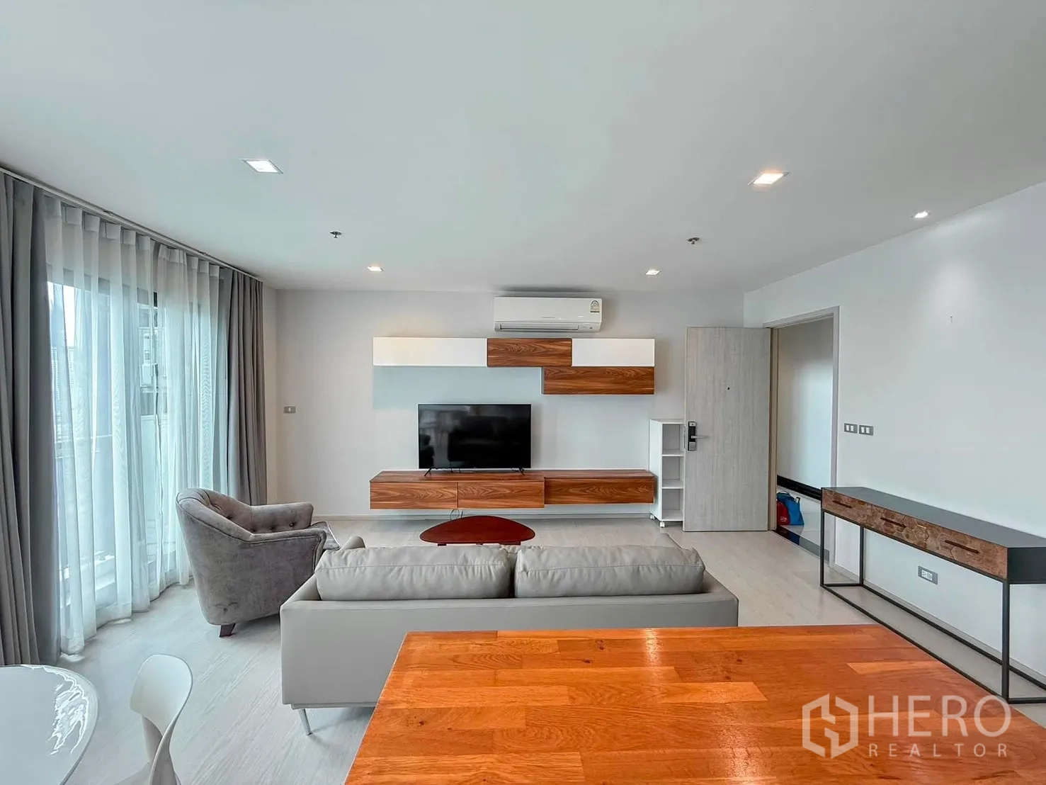 Condominium for rent in Khlong Toei, Bangkok - Living area facing kitchen with island, gray cabinets, and dining space.