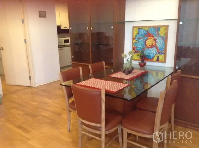 คอนโด ให้เช่าหรือขายในDin Daeng, Bangkok - มุมทานอาหารพร้อมโต๊ะกระจก เก้าอี้สีน้ำตาล พื้นไม้ และภาพศิลปะสีสันในคอนโดกรุงเทพฯ