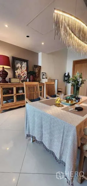 Condominium for sale in Sathon, Bangkok - Dining space with wooden chairs, pendant light and sideboard beside the kitchen.