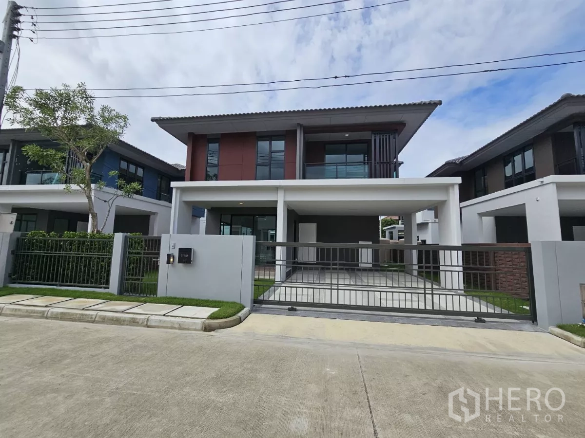 บ้าน ขายในLam Luk Ka, Pathum Thani - มุมมองจากถนนของบ้านสไตล์โมเดิร์น พร้อมประตูรั้วเหล็กและที่จอดรถคู่