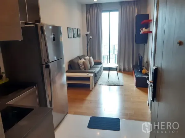 公寓 出租在Khlong Toei, Bangkok - 开放式客厅，配沙发、电视柜、阳台落地窗与带冰箱的小厨房。