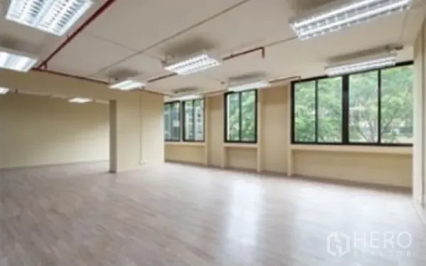 办公空间 出租在Chatuchak, Bangkok - 开放式办公室，木纹地板，多组荧光灯，红色管线外露，临窗望向树景。