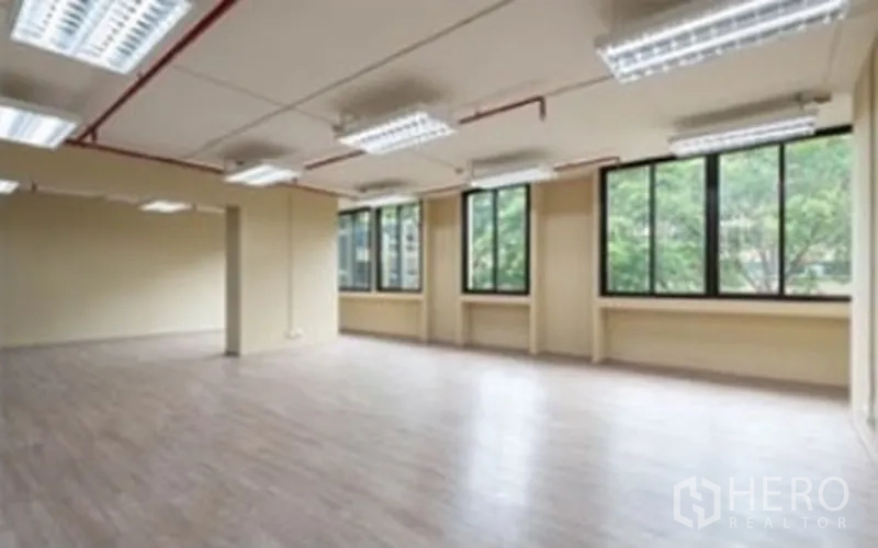 办公空间 出租在Chatuchak, Bangkok - 开放式办公室，木纹地板，多组荧光灯，红色管线外露，临窗望向树景。