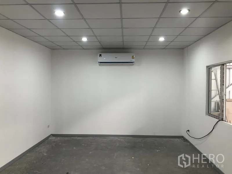 Warehouse for rent in Nonthaburi - Air-conditioned office room with drop ceiling, recessed lighting and internal window overlooking the warehouse floor.
