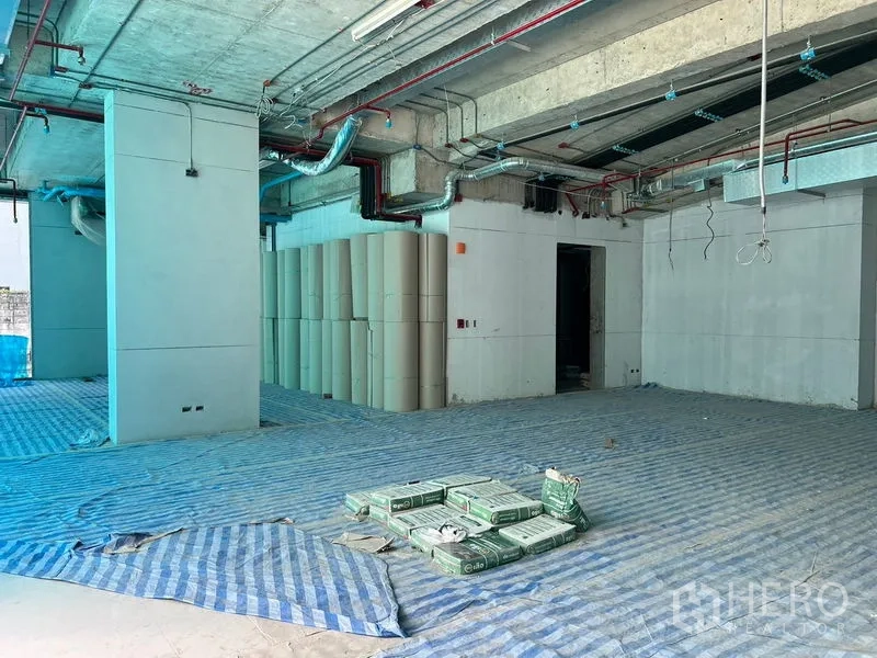 พื้นที่ขายปลีก ให้เช่าในKhlong Toei, Bangkok - พื้นค้าปลีกระหว่างก่อสร้าง มีเสากลาง วัสดุเรียงกอง และงานระบบเพดาน