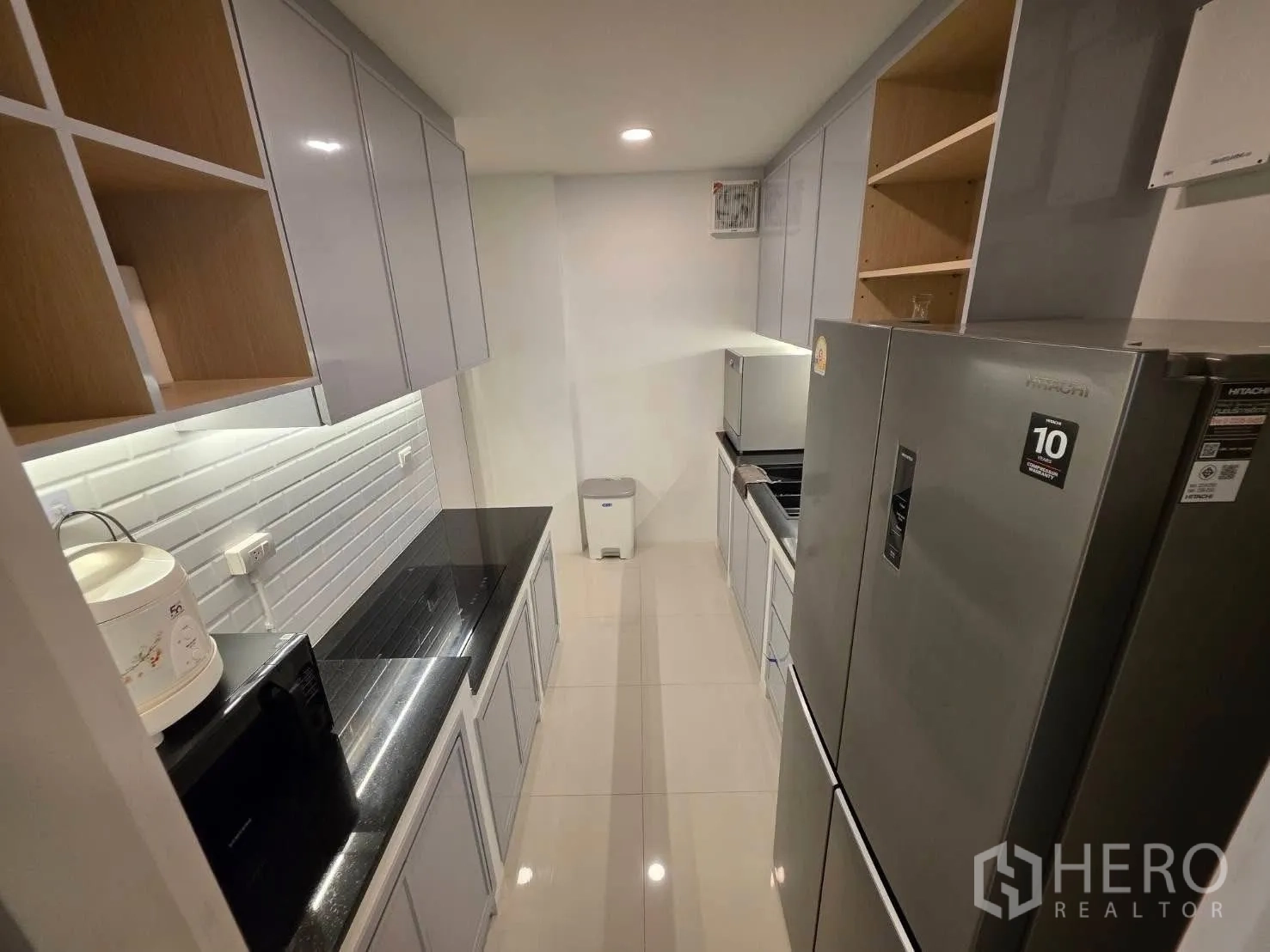 Detached House for rent or sale in Bang Phli, Samut Prakan - Sleek galley kitchen with glossy cabinets, black countertop and large fridge.