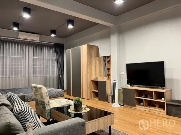 Shophouse for sale in Bang Kho Laem, Bangkok - Spacious living room with grey sofa, TV console, wood floors and full-height curtains.