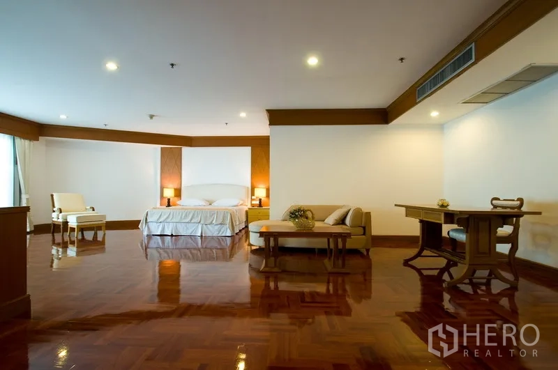 房间 出租在Khlong Toei, Bangkok - 宽敞主卧，抛光木地板，带休息区与柔和灯光。