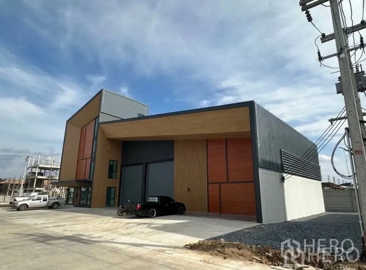 โกดัง for sale in Lam Luk Ka, Pathum Thani - ด้านหน้าอาคารติดถนน พร้อมประตูม้วนขนาดใหญ่และกันสาดลานโหลด