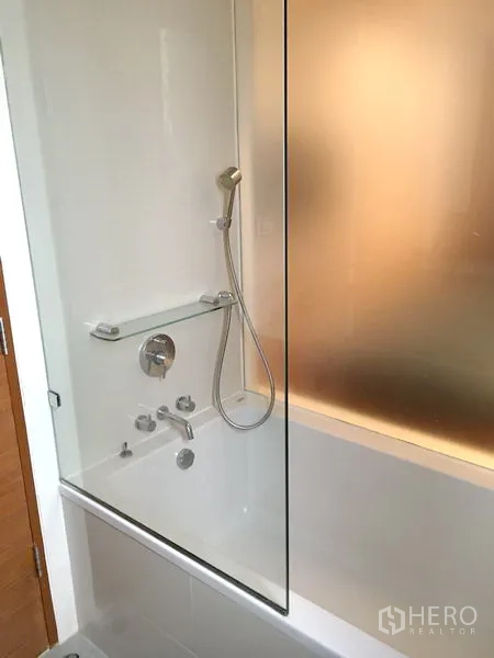 คอนโด ให้เช่าหรือขายในKhlong Toei, Bangkok - อ่างอาบน้ำสีขาว พร้อมฝักบัวมือถือและฉากกระจกในห้องน้ำสไตล์โมเดิร์น