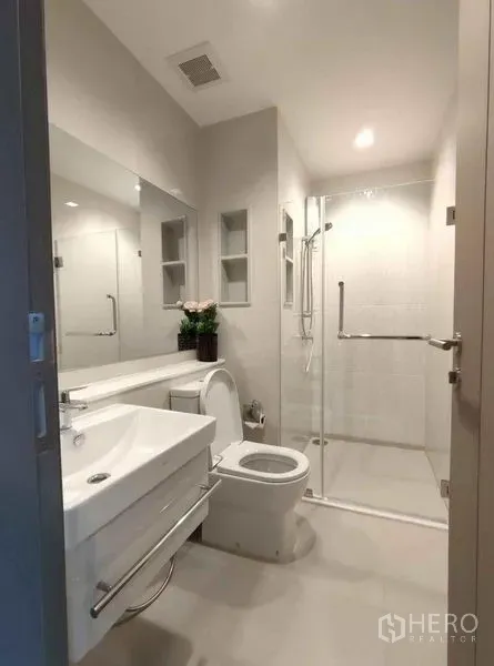 公寓 出租在Ratchathewi, Bangkok - 明亮现代卫浴，配玻璃淋浴间、洗手台与坐便器。