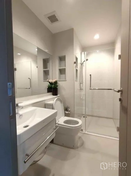 公寓 出租在Ratchathewi, Bangkok - 明亮现代卫浴，配玻璃淋浴间、洗手台与坐便器。