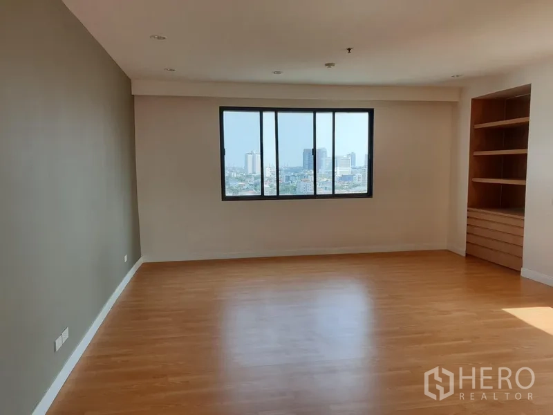 Condominium for rent in Watthana, Bangkok - Large bedroom with wood flooring, picture window with city view and built-in corner shelving.