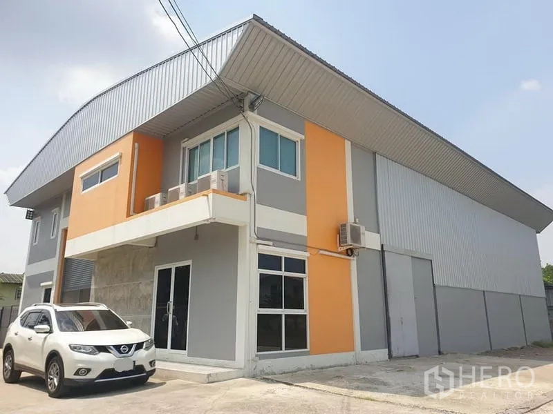 Warehouse for rent in Bang Kapi, Bangkok - Modern two-storey warehouse exterior in Bang Kapi with orange-grey facade, parking and a high roller shutter.