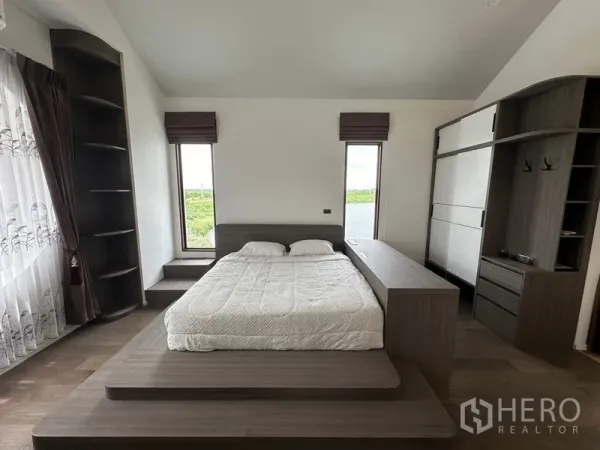 Detached House for sale in Sai Noi, Nonthaburi - Close view of platform bed and custom wardrobes with tall windows bringing in natural light.
