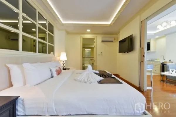 房间 出租在Khlong Toei, Bangkok - 温馨卧室，特大床、镜面墙、灯带天花与浴室门。