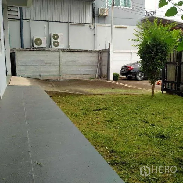 工厂 出租或出售在Ban Phaeo, Samut Sakhon - 建筑侧院草坪与车道，旁设室外空调机组