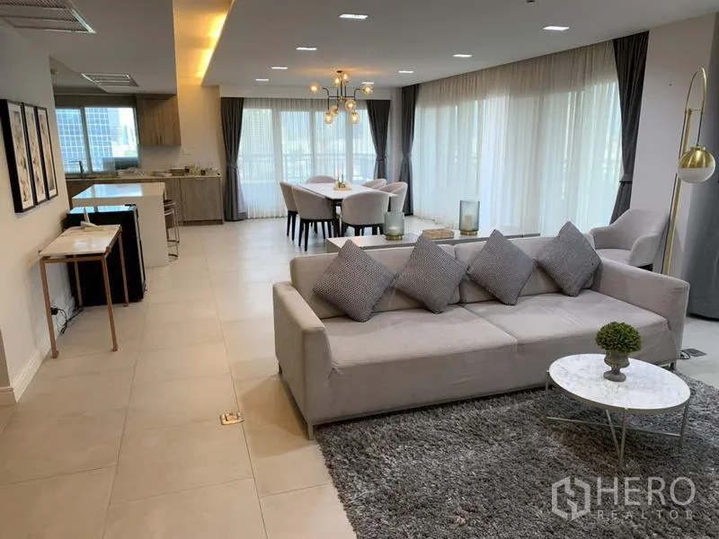 Condominium for rent in Sathon, Bangkok - Spacious living and dining area with floor-to-ceiling curtains and city-facing windows.