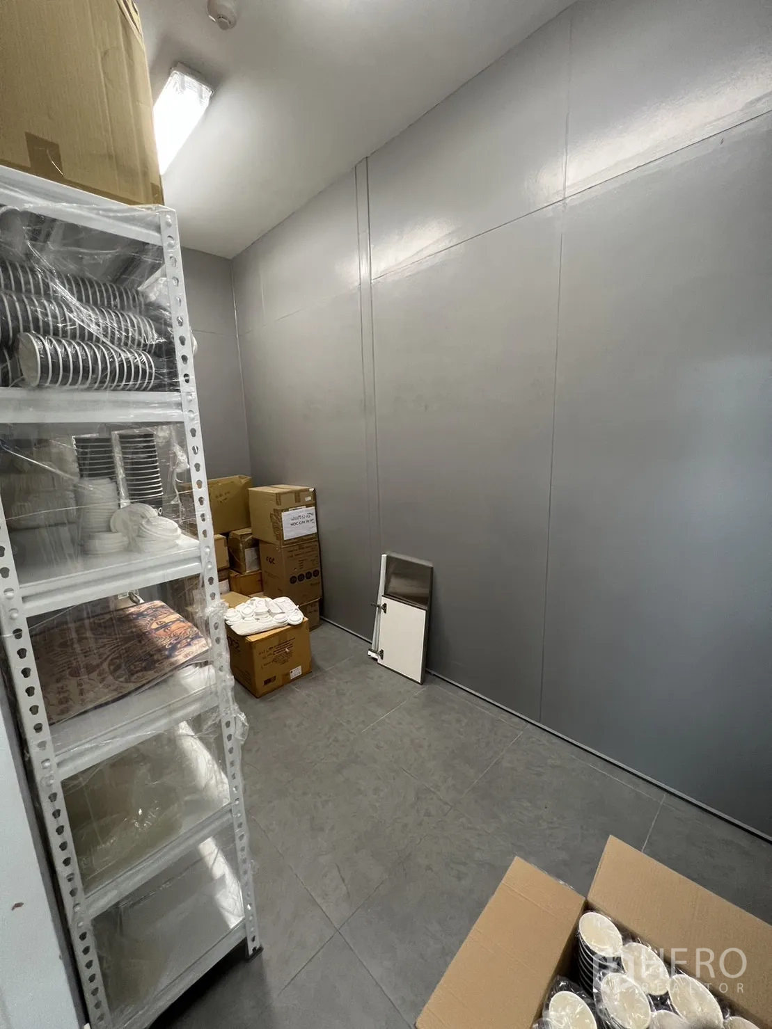 零售空间 出租在Khlong Toei, Bangkok - 整洁的储藏区，灰色墙面、瓷砖地与顶灯。