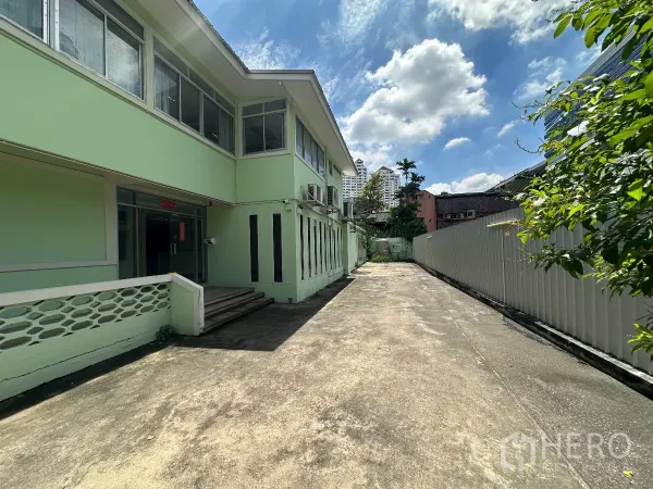 零售空间 出租在Watthana, Bangkok - 建筑侧面入口与沿侧的长车道，晴空之下。