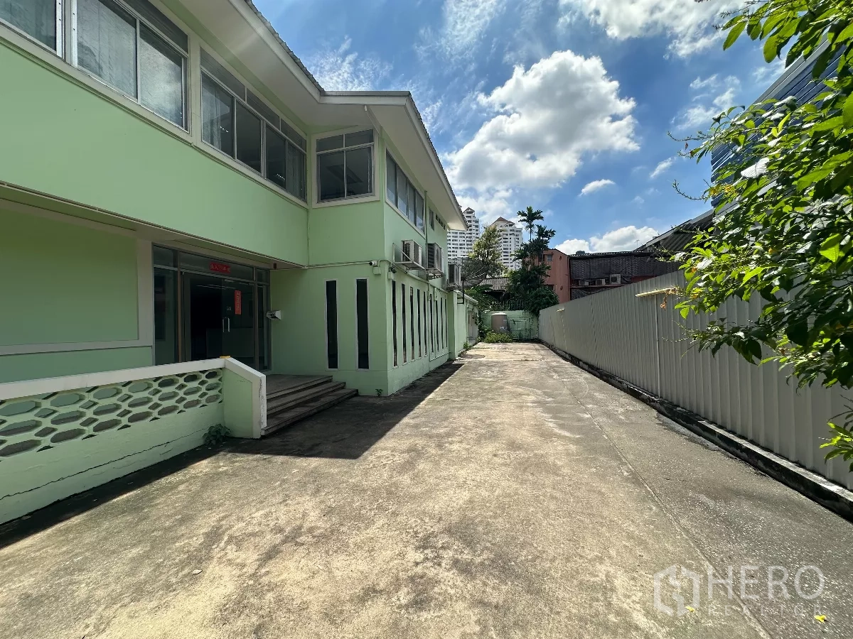 零售空间 出租在Watthana, Bangkok - 建筑侧面入口与沿侧的长车道，晴空之下。