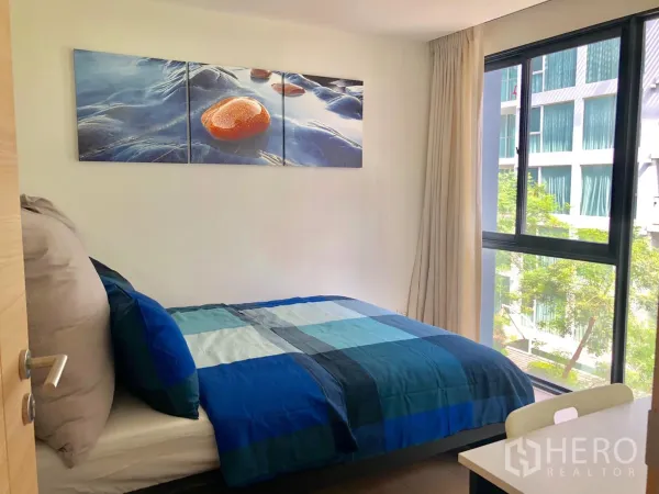 Condominium for rent in Watthana, Bangkok - Sunlit bedroom with double bed, large window and courtyard view.