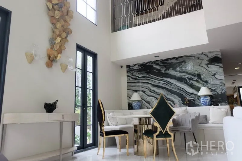 ทาวน์เฮาส์ ให้เช่าในKhlong Toei, Bangkok - โถงนั่งเล่นเพดานสูงโปร่ง โซฟาสีขาว และผนังลายหินอ่อนเด่นสะดุดตา