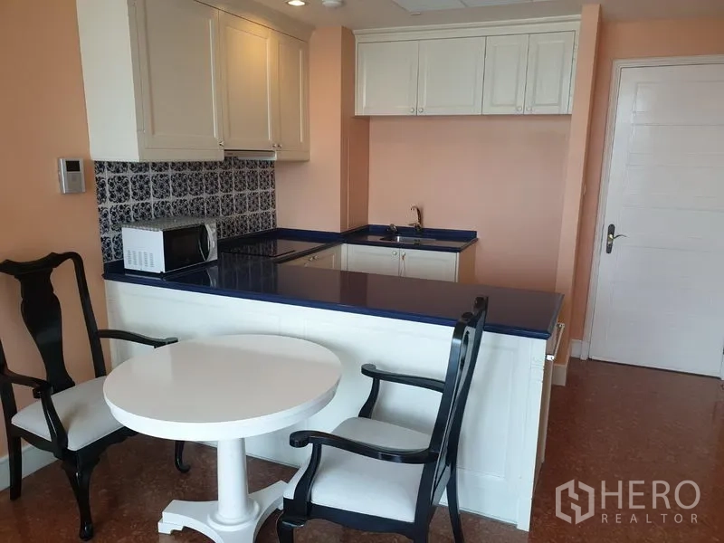 คอนโด ให้เช่าในKhlong Toei, Bangkok - ครัวบิวท์อินท็อปสีน้ำเงิน ตู้สีขาว กระเบื้องลาย และโต๊ะทานอาหารขนาดเล็ก