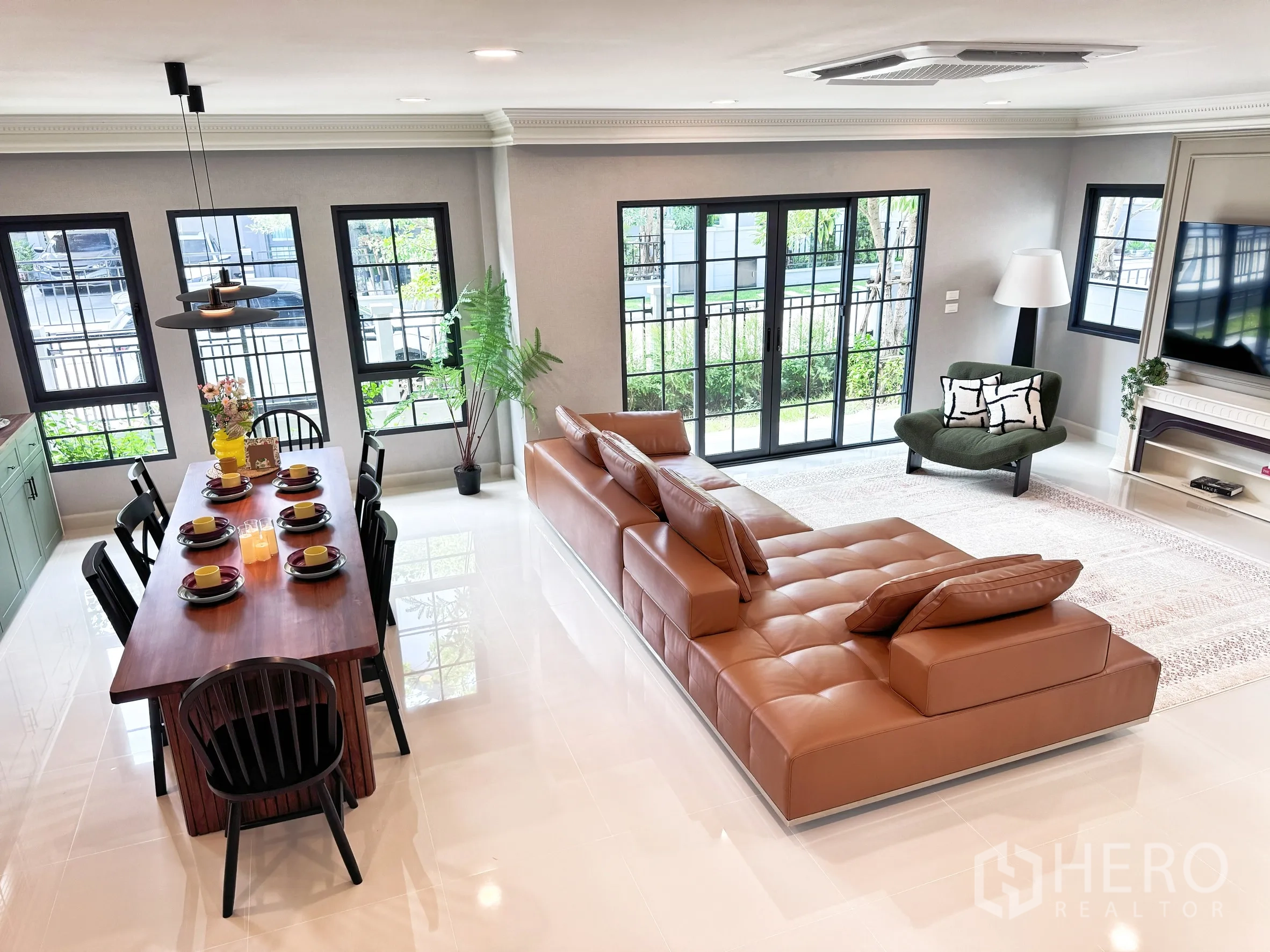 Detached House for rent in Bang Phli, Samut Prakan - Open-plan living and dining with many black-framed windows and access to the garden.