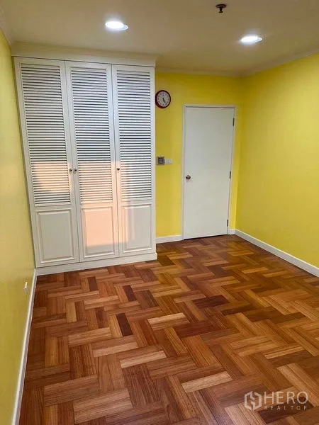 คอนโด ให้เช่าหรือขายในBangkok - ห้องนอนที่สองพร้อมตู้เสื้อผ้าบิลท์อินสีขาวและผนังสีเหลือง