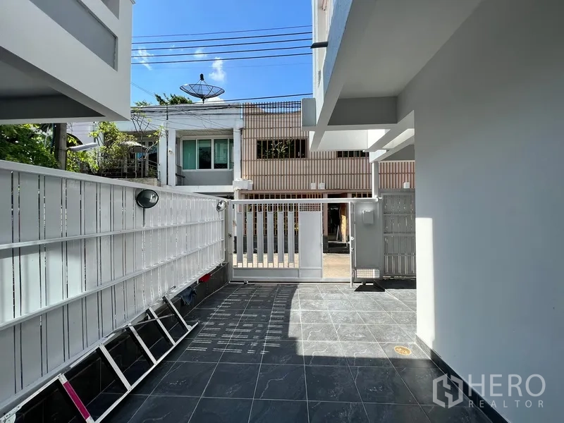 带办公室的家 出租在Watthana, Bangkok - 前院铺砖庭院与安全金属大门，可作停车位。