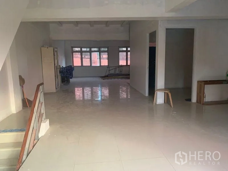 Shophouse for rent in Prawet, Bangkok - Ground level hall with staircase, partitioned rooms and reflective tiled floor.