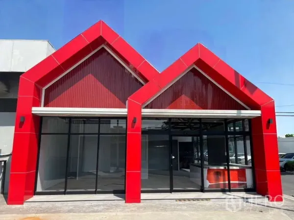 零售空间 出租 - 红色双山墙立面与整面落地玻璃的临街商铺外观。