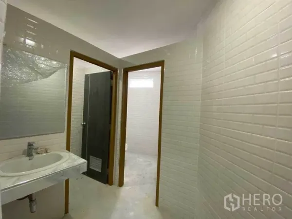 零售空间 出售在Khlong Toei, Bangkok - 卫生间过道，白砖墙，可见洗手台与两个隔间门