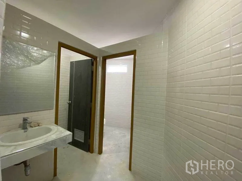 零售空间 出售在Khlong Toei, Bangkok - 卫生间过道，白砖墙，可见洗手台与两个隔间门