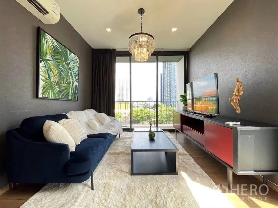 คอนโด for rent in Watthana, Bangkok - ห้องนั่งเล่นสว่างมีโซฟาสีน้ำเงิน โคมแชนเดอเลียร์ ตู้ทีวี และกระจกสูงเปิดสู่ระเบียง
