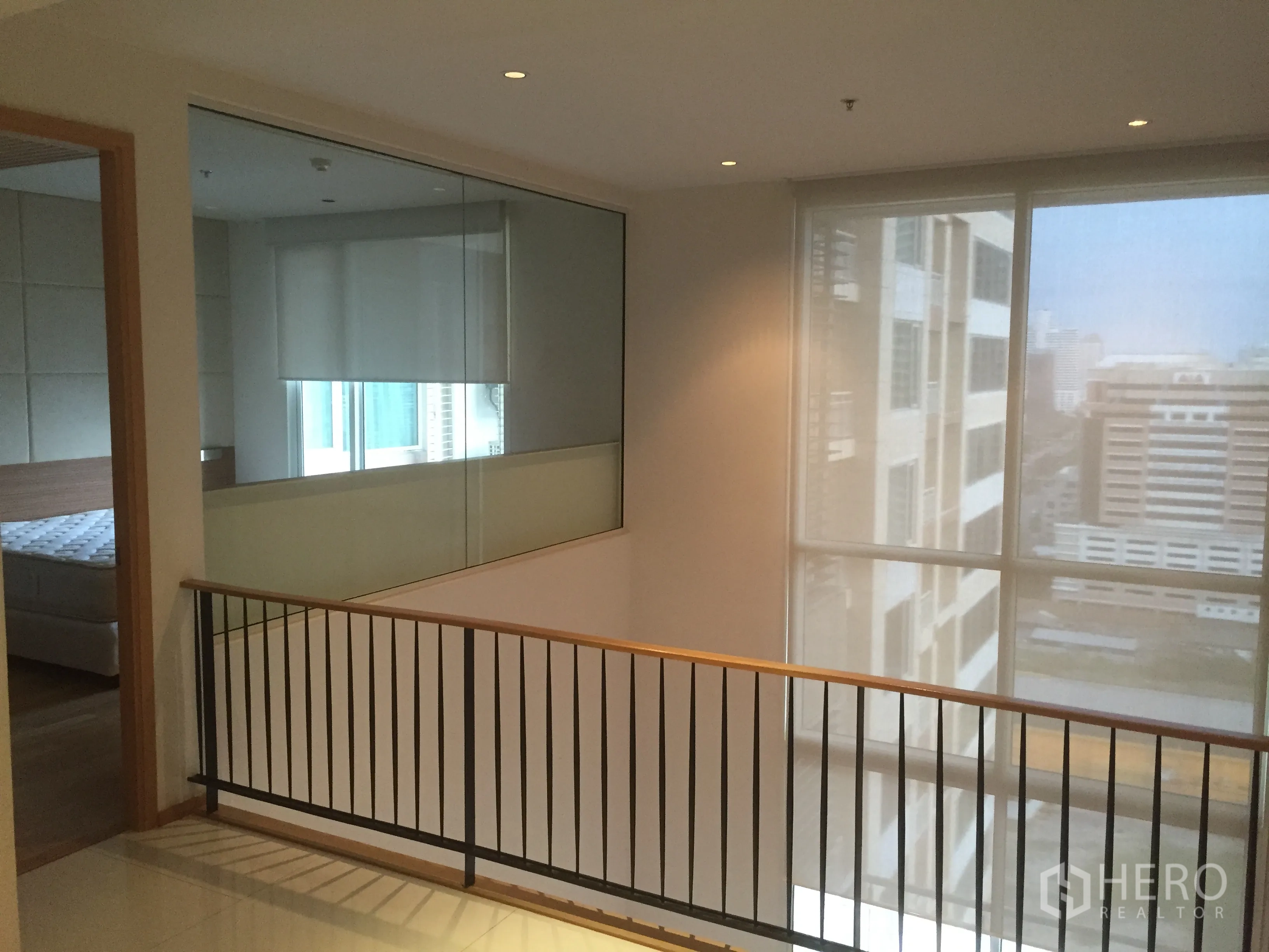 Condominium for rent in Sathon, Bangkok - Upper-floor landing with metal railing and floor-to-ceiling windows overlooking Sathon.