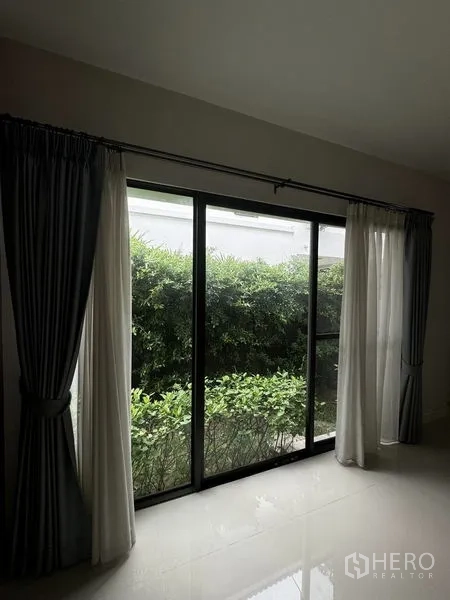 Detached House for rent in Samut Prakan - Sliding glass doors opening to small hedged garden and greenery.