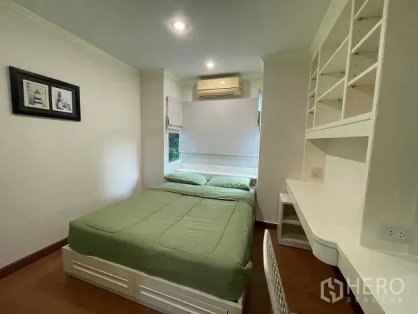 คอนโด ให้เช่า - ห้องนอนอบอุ่น ชุดผ้าปูสีเขียว โต๊ะทำงานและชั้นบิวท์อิน พร้อมแอร์หน้าต่าง