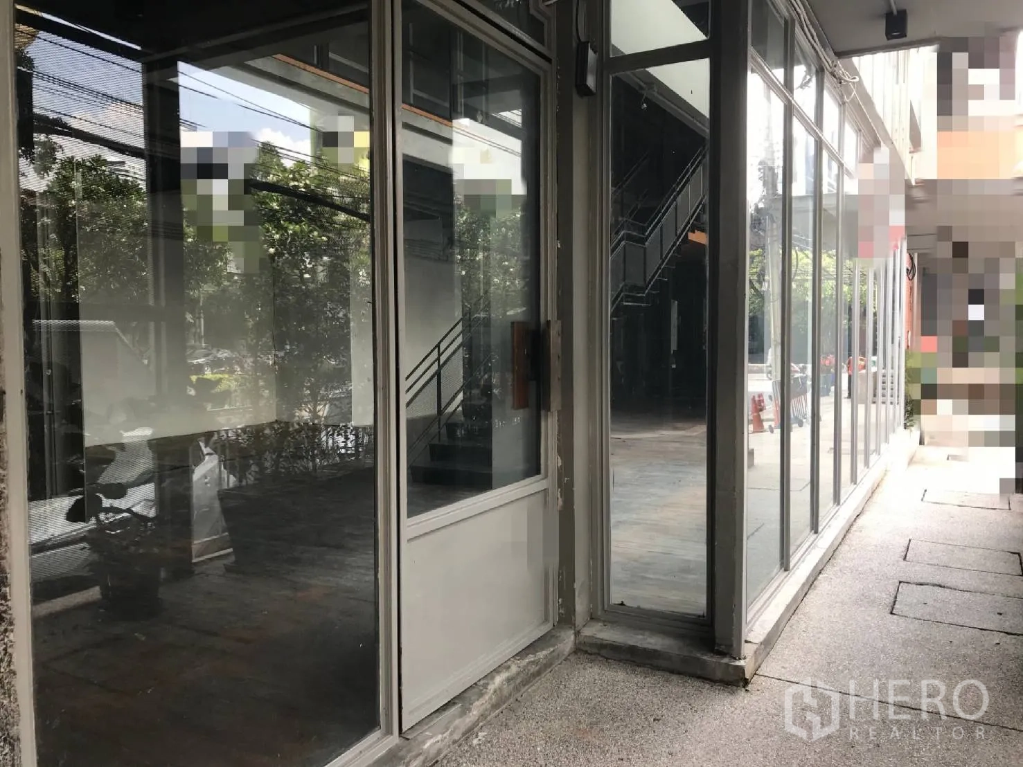 零售空间 出租在Watthana, Bangkok - 玻璃转角入口的临街商铺，可见室内楼梯