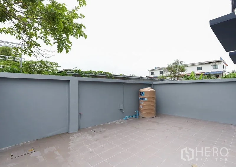 Shophouse for sale in Lam Luk Ka, Pathum Thani - Walled rear patio with utility points and a water tank.
